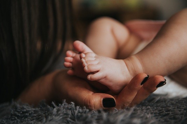 Maman qui tient le pied d'un bébé dans sa main